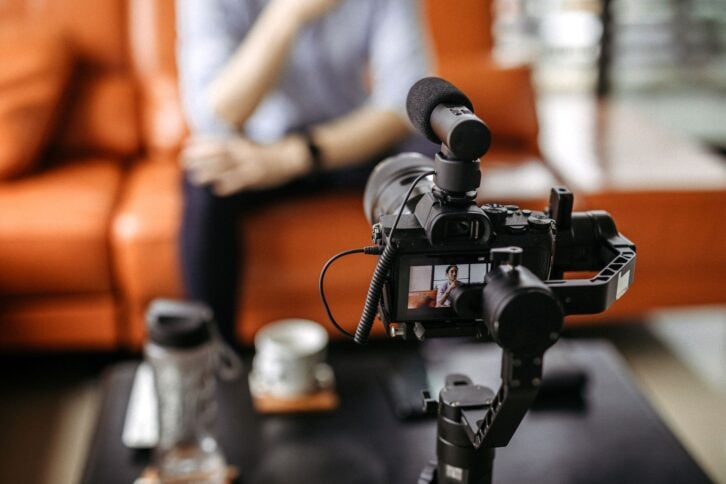 Influencer  recording a video with professional camera, focus on foreground