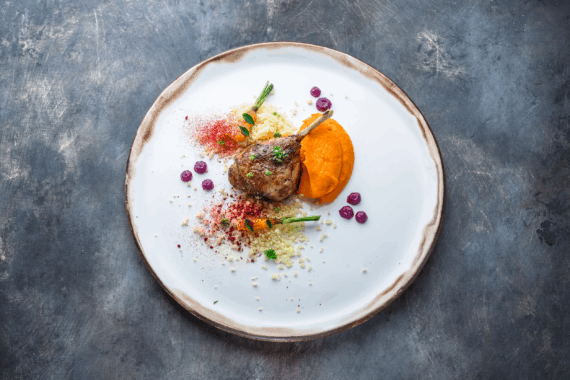 Duck leg confit with batat puree, carrots and couscous, restaurant meal stock photo