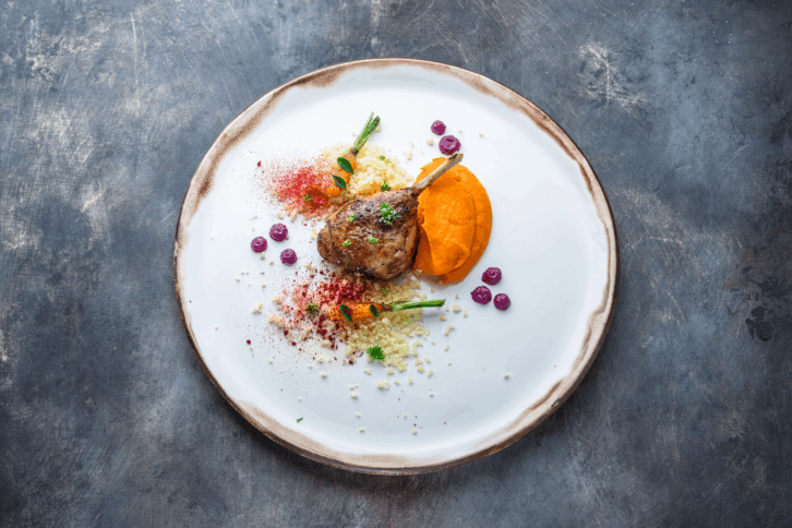 Duck leg confit with batat puree, carrots and couscous, restaurant meal stock photo