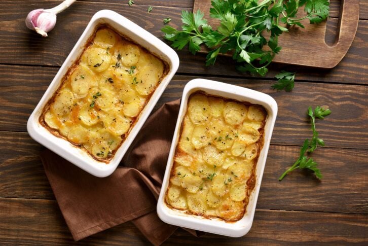 Potato gratin in baking dish over wooden background. Top view, flat lay