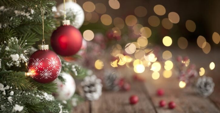 Christmas tree with red and white baubles and lights against an old wood background