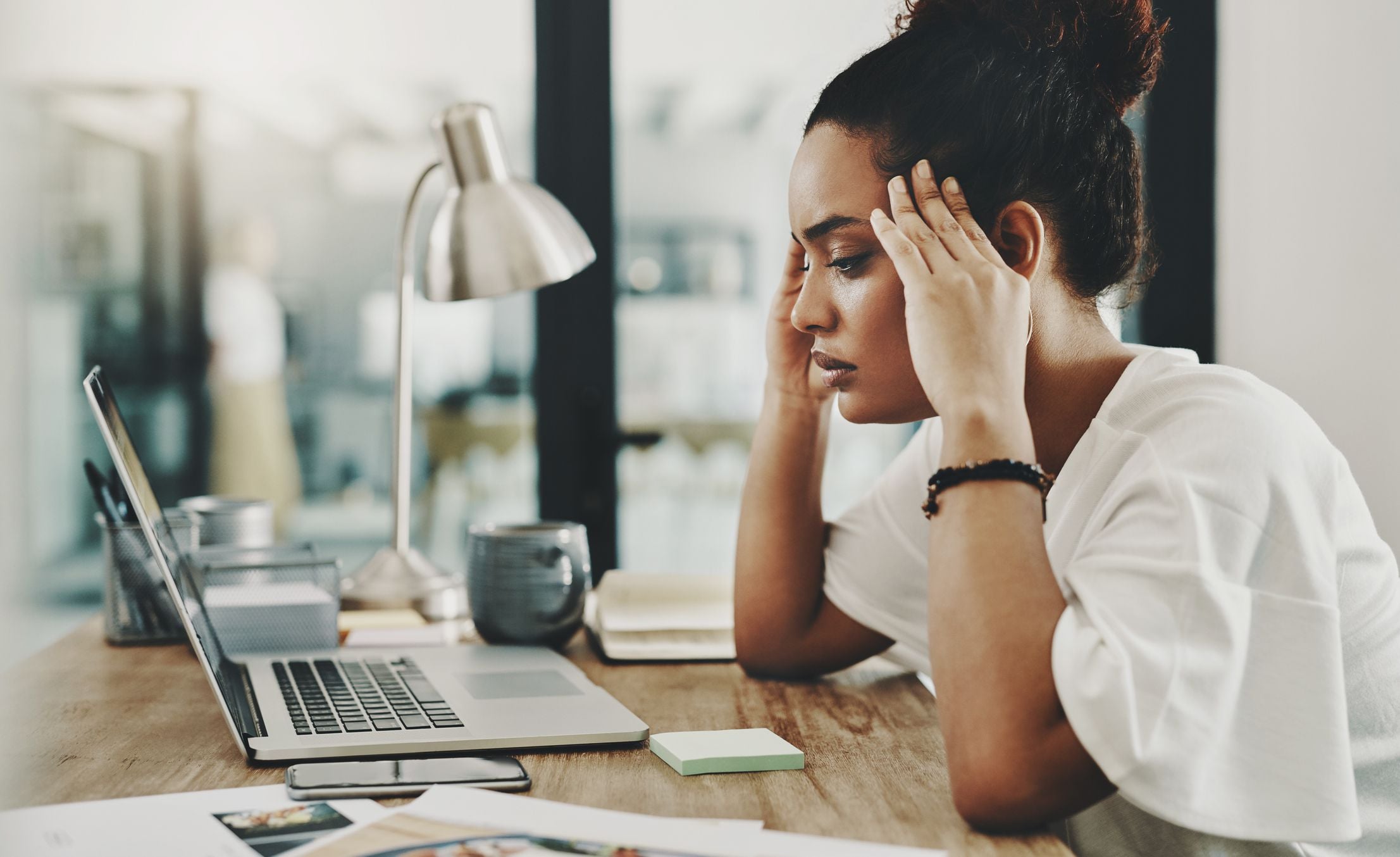 A professional staring at a cluttered desk with a look of exhaustion and confusion, symbolizing career stagnation despite hard work.