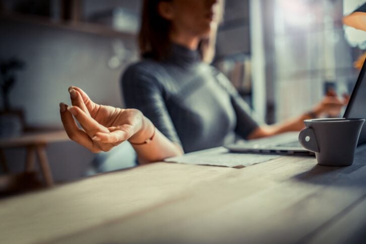 Woman at her desk in office, meditating