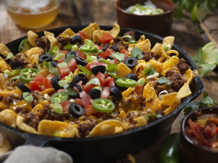 Baked Frito Pie (Chili Corn Chip Nachos) with Black Olives, Tomatoes, Green Onions, Jalapenos, Salsa, Guacamole and Sour Cream