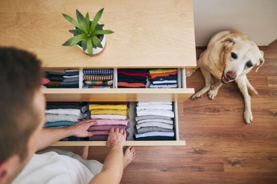 Organizing and cleaning home. Man preparing orderly folded t-shirts in drawer.