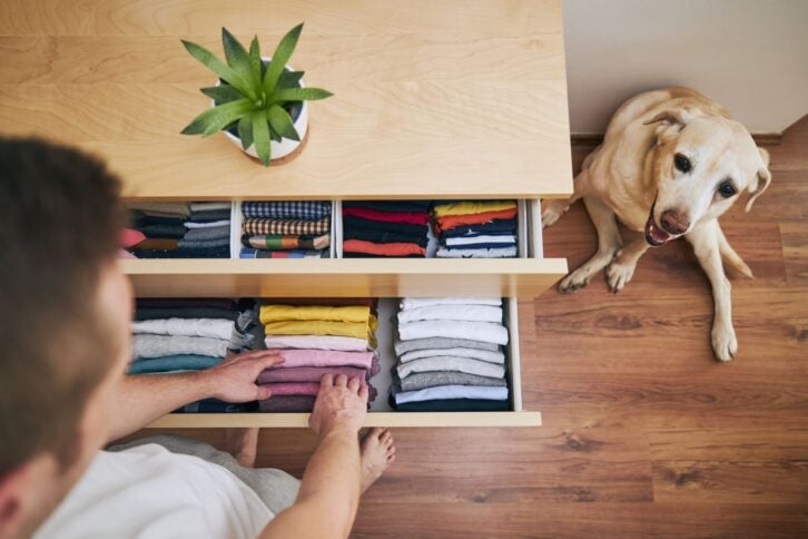 Organizing and cleaning home. Man preparing orderly folded t-shirts in drawer.