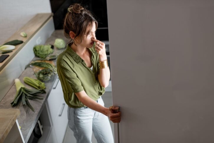 Young woman looking into the fridge, feeling hungry at night. Concept of not regular eating and overeating at night