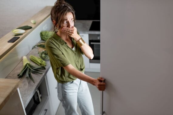 Young woman looking into the fridge, feeling hungry at night. Concept of not regular eating and overeating at night