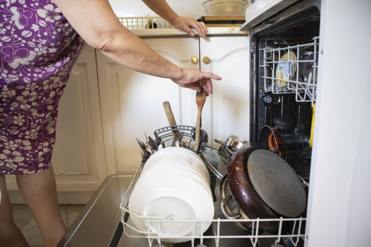 Woman using dishwasher in the kitchen
