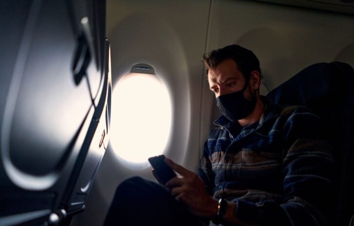 Young man with wifi on a plane checking the news during coronavirus pandemic
