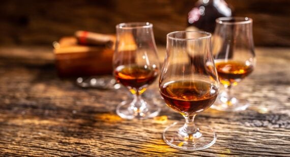 Caribbean rum in modern glasses with a bottle of rum and a cigar in the background.