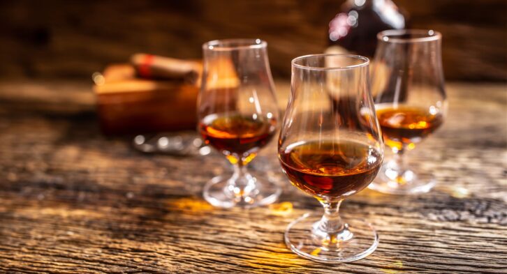 Caribbean rum in modern glasses with a bottle of rum and a cigar in the background.