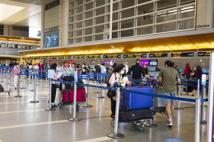 Travelers with luggage at LAX departure hall with face masks