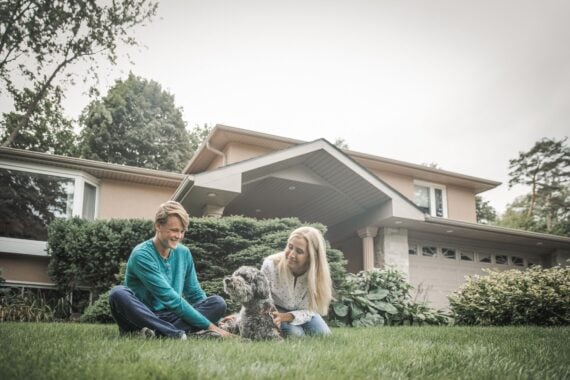 mother and her teenager son relaxing in front of the house on the lawn, with a dog