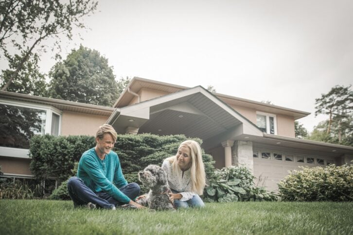 mother and her teenager son relaxing in front of the house on the lawn, with a dog