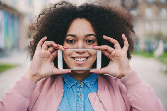 Young woman showing photo of perfect toothy smile after professional teeth whitening