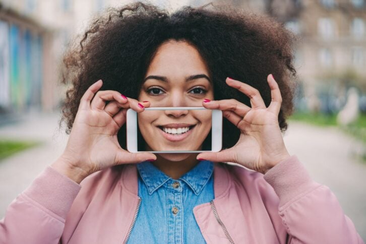 Young woman showing photo of perfect toothy smile after professional teeth whitening