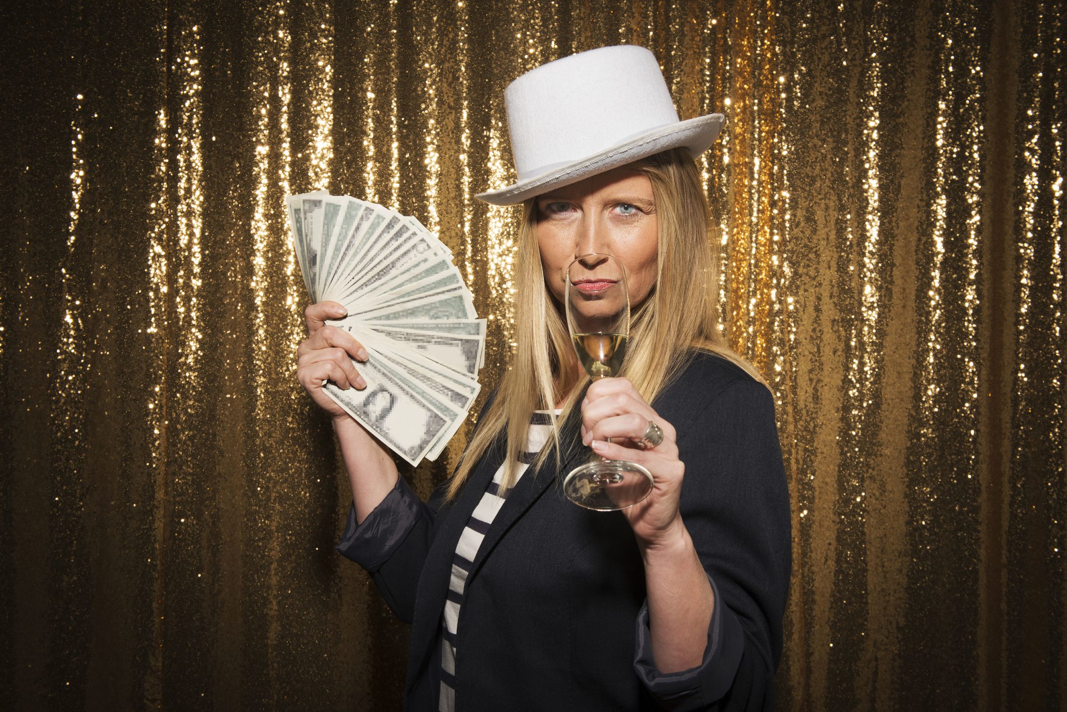 Portrait of woman drinking champagne and holding banknotes while enjoying party.