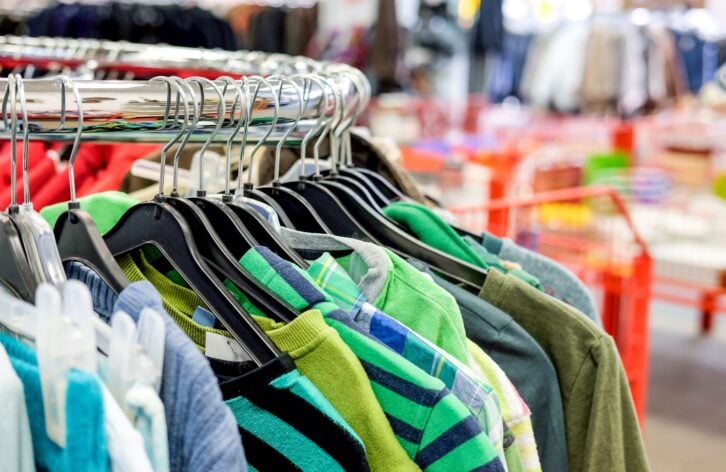 Different used clothes for men, women and children on the rack in a second hand shop or thrift store - selective focus with very little depth of field for adequate copyspace
