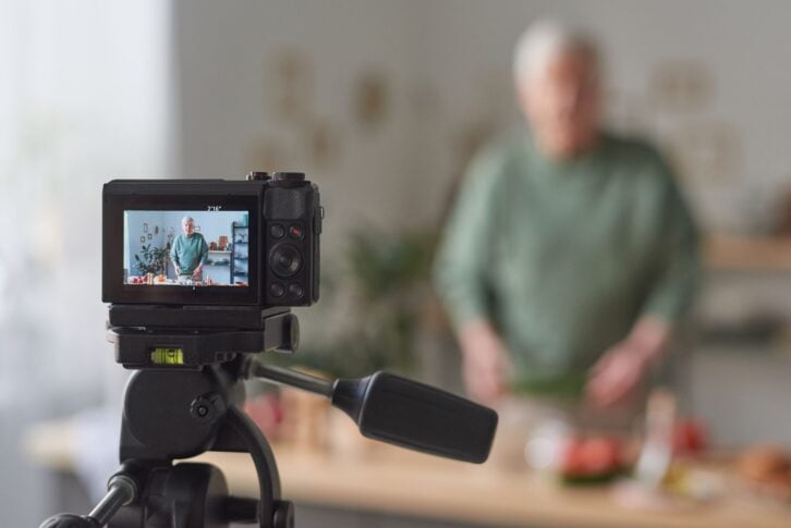 Senior food blogger shooting on camera his blog about food in the kitchen