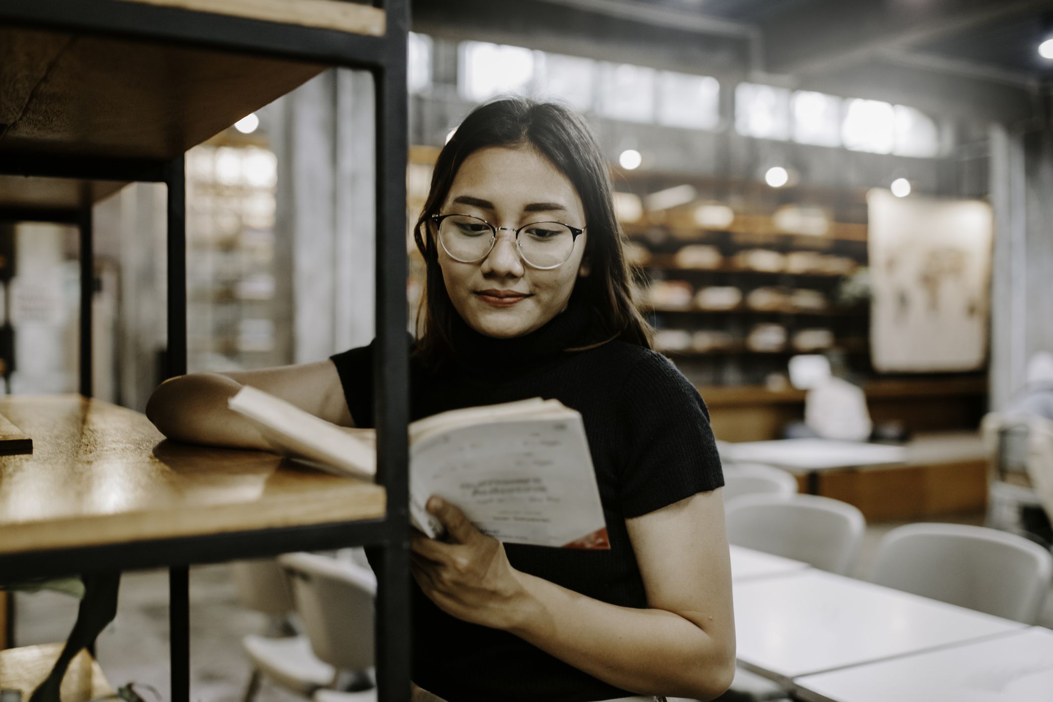 asian woman choosing a book from bookshelf