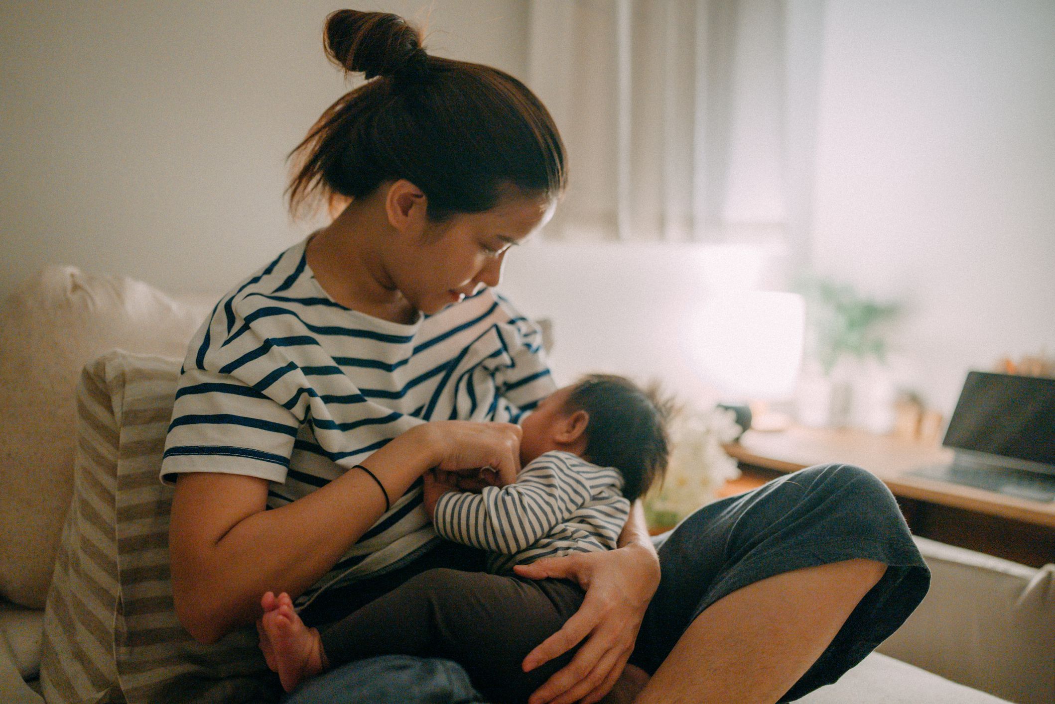 Asian mother breastfeeding baby at home.