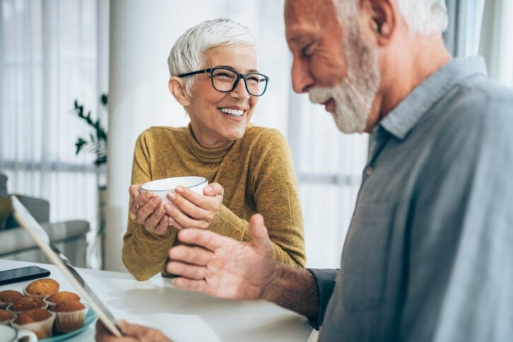 Shot of cheerful mature couple sitting on the table at home and using digital tablet.