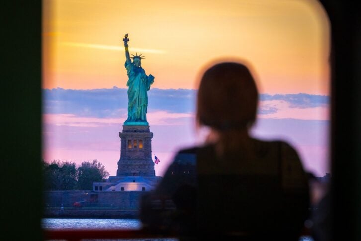 A young woman watches the Statue of Liberty, from the Staten Island Ferry