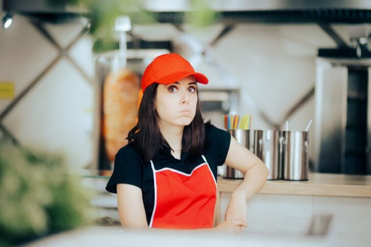 Unhappy restaurant employee feeling tired and bored having a break thinking of financial difficulties on a minimum wage