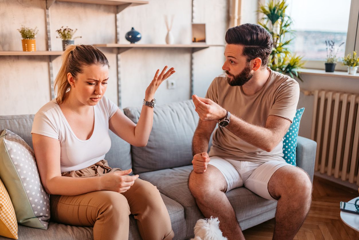 A couple arguing while they sit on the couch.