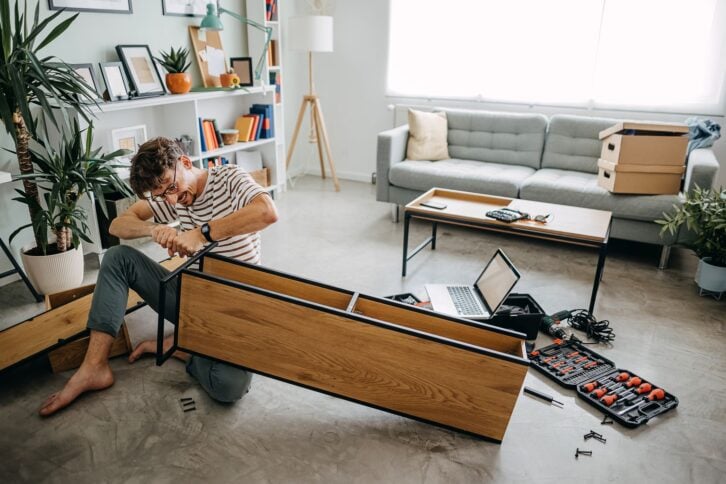 Man In New Home Putting Together Self Assembly Furniture