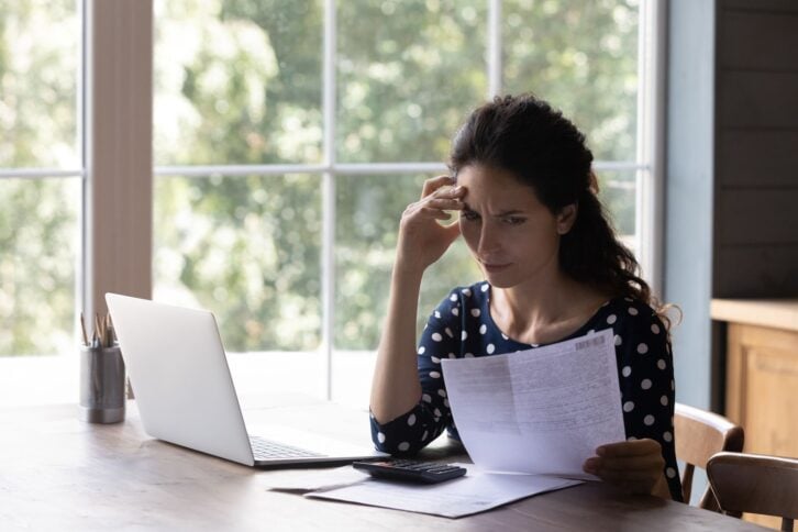 Concern housewife checking utility bill, seeing mistaken too high costs. Worried woman reading paper invoice with doubt, having problems with loan, mortgage, taxes fee payment. Personal budget concept