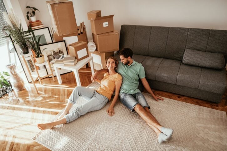 Couple moving in the new apartment, unpacking cardboard boxes and moving the furniture in