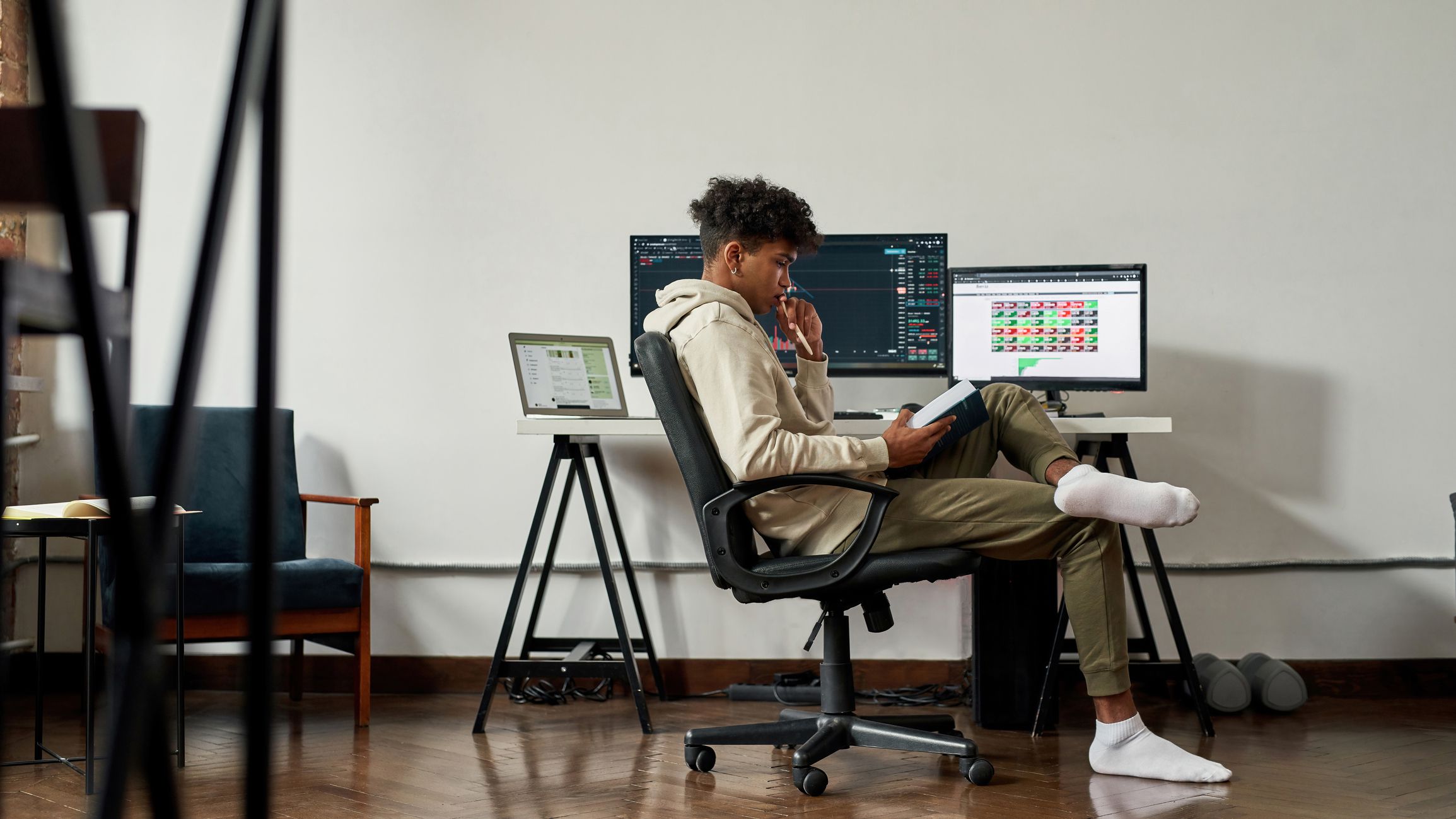 Candid shot African American young man work trade online on computers at home. Ethnic male trader investor analyze financial graph chart on stock market. Cryptocurrency investment, finance concept.