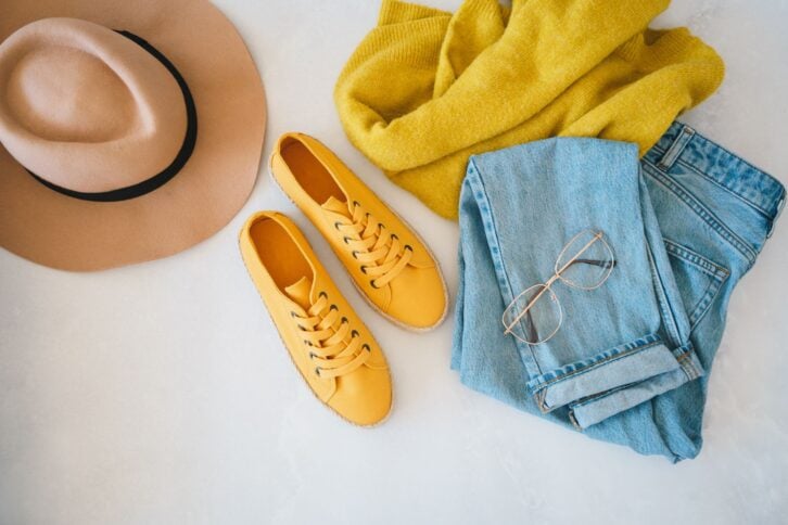 Flat lay with woman's clothes and accessories: jeans, sneakers, sweater and fedora hat