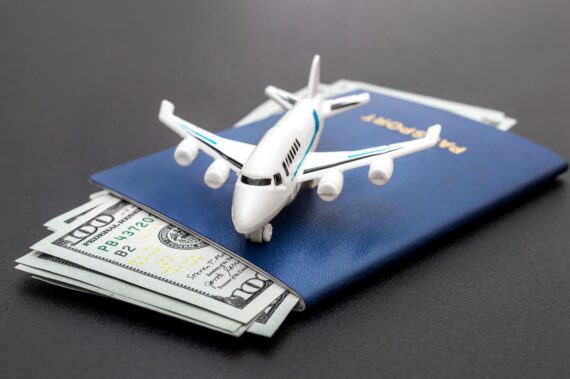 Airplane toy with passports and money on black background. Air trip and vacation.