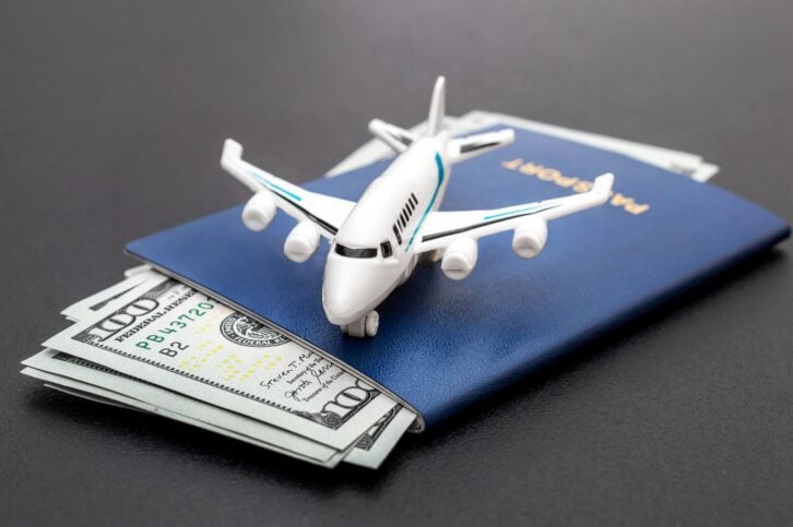 Airplane toy with passports and money on black background. Air trip and vacation.