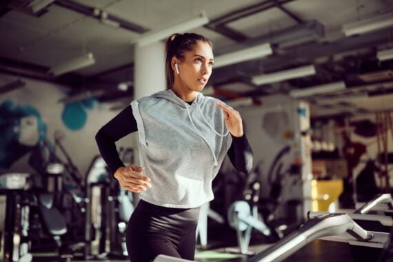 Young female runner exercising on treadmill in a gym.