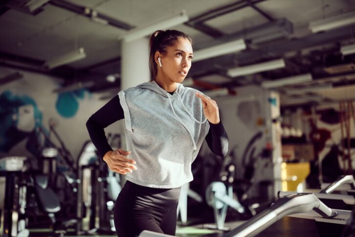 Young female runner exercising on treadmill in a gym.