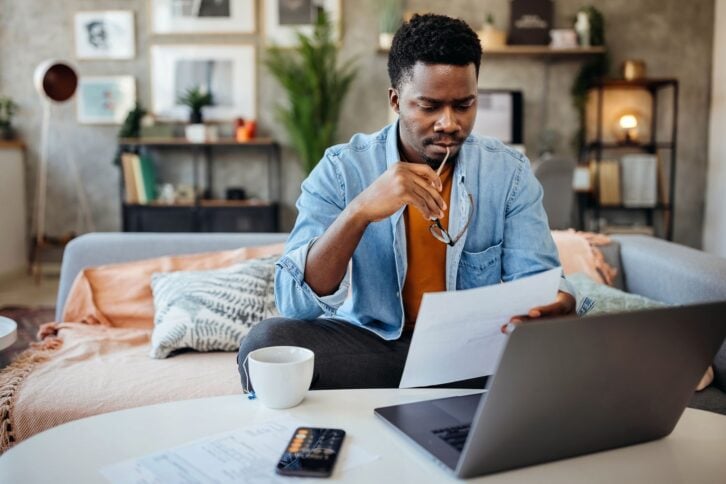 Shot of a young man going over his finances at home