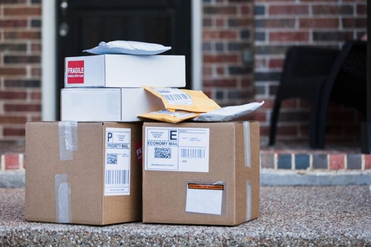 A stack of packages await delivery or pick up on the front porch of the residence.