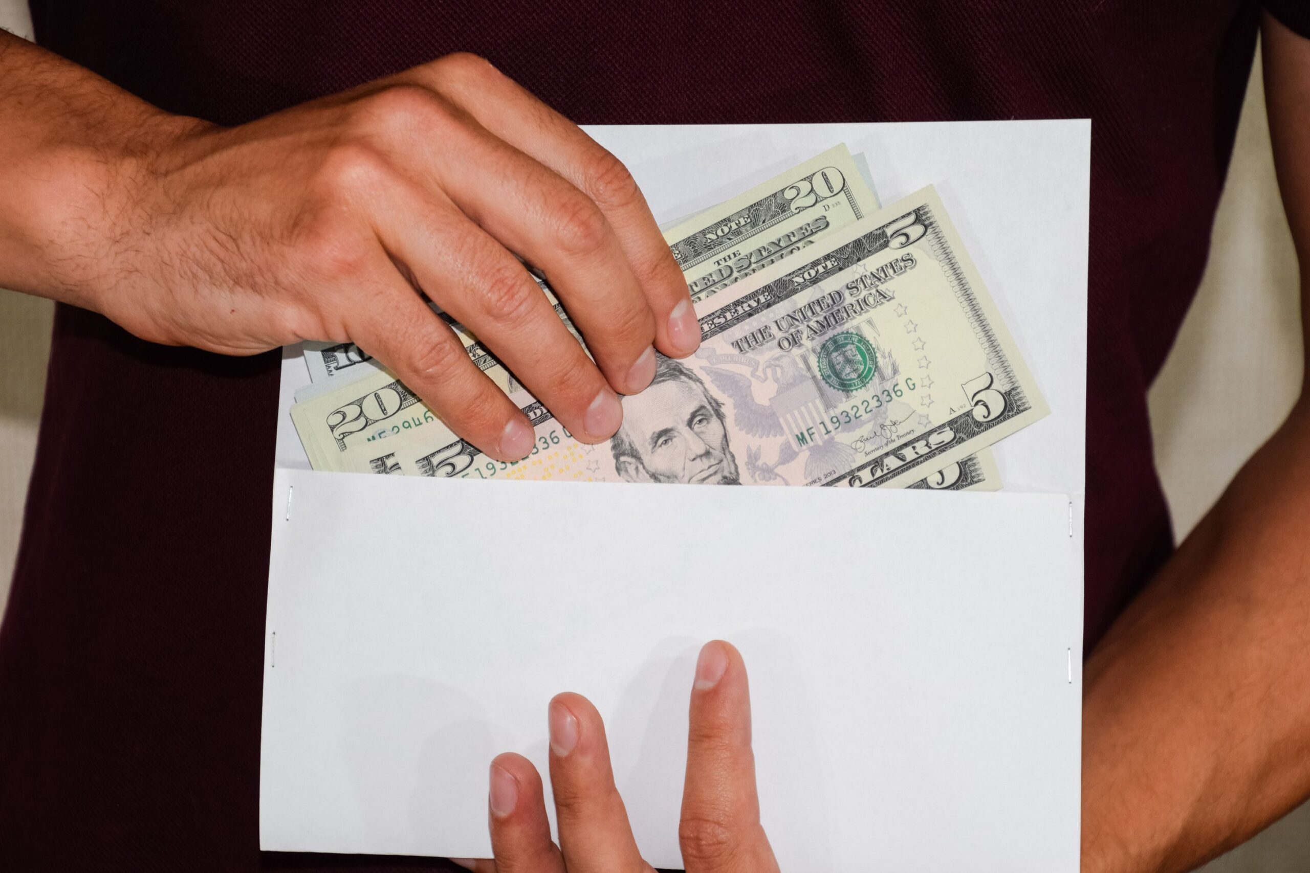 Money in a white envelope in the hands of a man. Dollars, a wad of dollars.