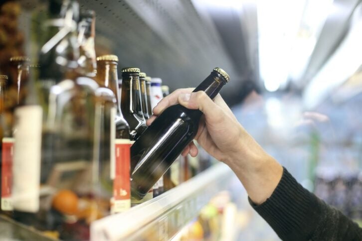 Unrecognizable man buying beer in a supermarket store.