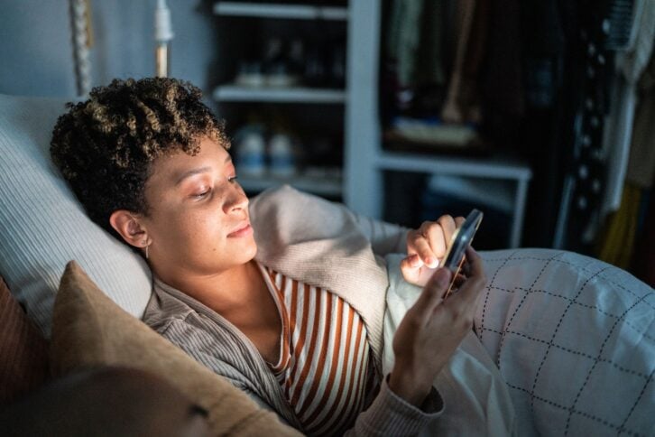 Young woman using smartphone on the bed