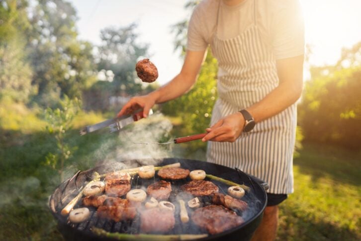 Unrecognizable male chef, grilling the chicken and beef meat, on the bbq grill, during bbq party