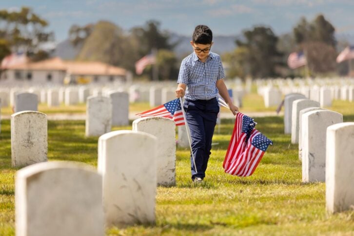 High quality stock photos of a young boy placing American flags on veterans graves at a veterans cemetery on Memorial Day.