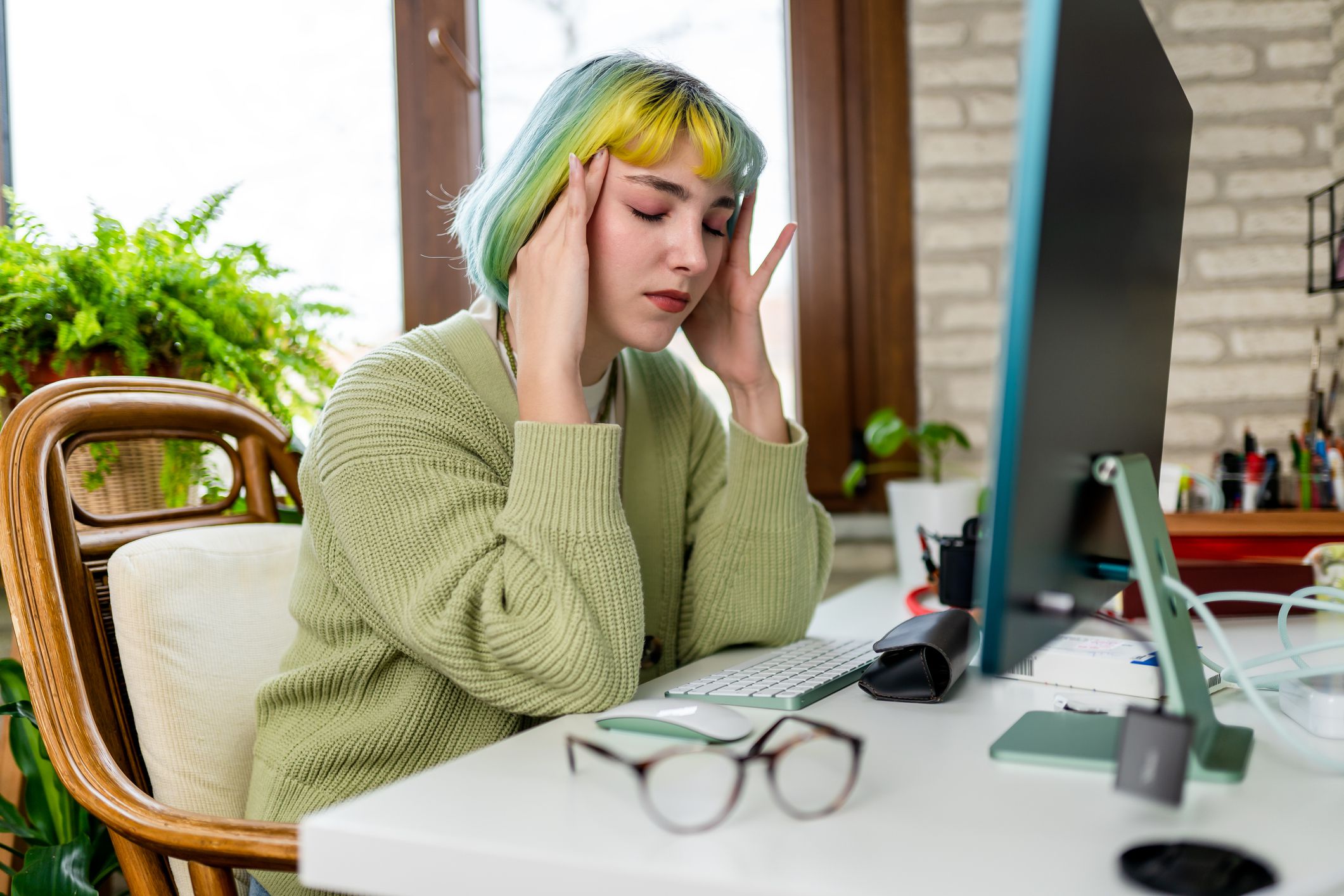 Young woman suffering from headache from too much computer use and work