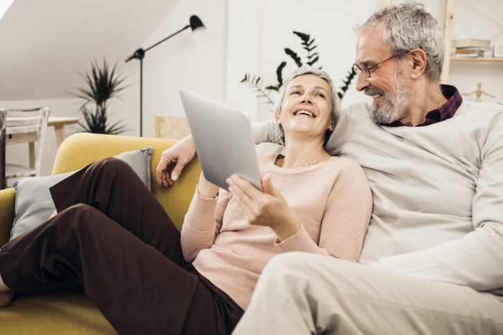 Happy senior couple using digital tablet and enjoying at home.