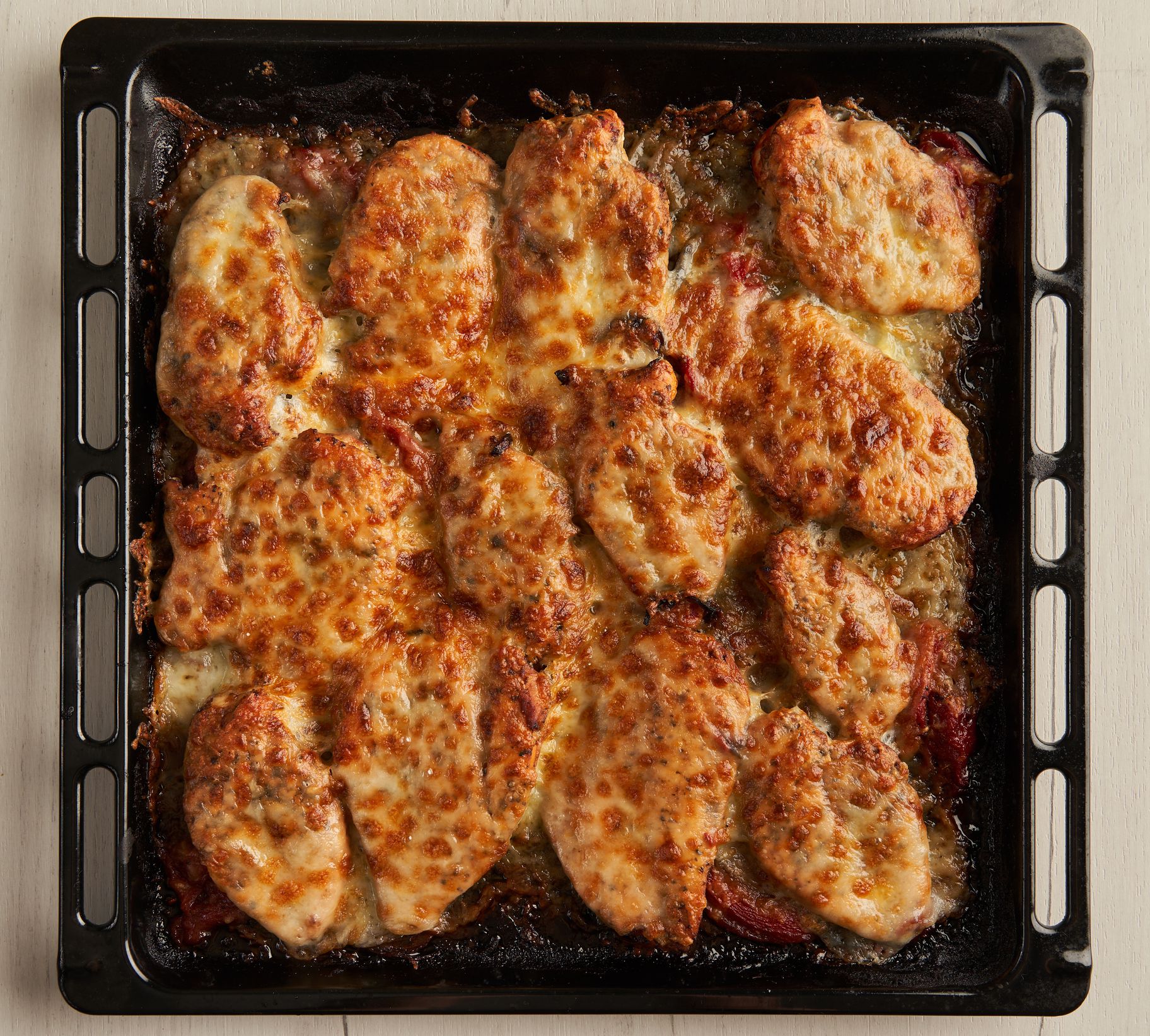 Mediterannean chicken breast oven baked with melted parmesan and cheddar in a tray