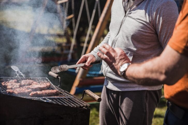 Man grilling meat on a barbecue party at his backyard
